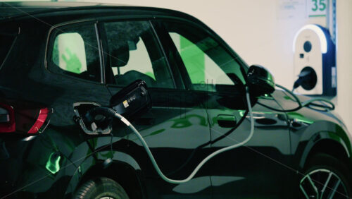 Video - Close up view of a black electric car plugged into a charging station