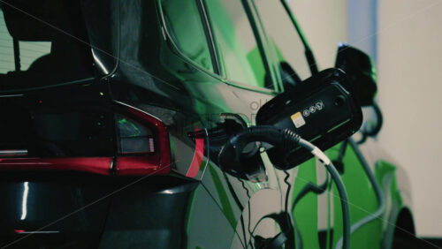Video - Close up view of a black electric car plugged into a charging station