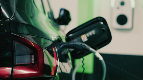 Video - Close up view of a black electric car plugged into a charging station