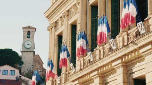 Video - Wide shot of a historic building decorated with French tricolor flags under clear daylight