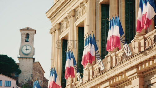 Video - Wide shot of a historic building decorated with French tricolor flags under clear daylight