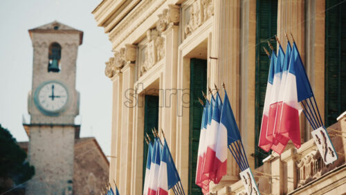 Video - Wide shot of a historic building decorated with French tricolor flags under clear daylight