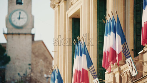 Video - Wide shot of a historic building decorated with French tricolor flags under clear daylight