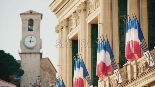 Video - Wide shot of a historic building decorated with French tricolor flags under clear daylight