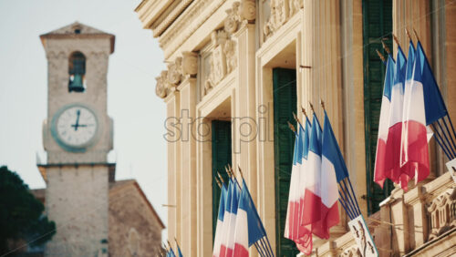 Video - Wide shot of a historic building decorated with French tricolor flags under clear daylight