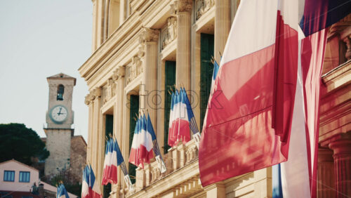 Video - Wide shot of a historic building decorated with French tricolor flags under clear daylight