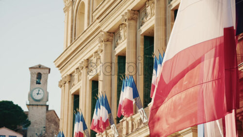 Video - Wide shot of a historic building decorated with French tricolor flags under clear daylight