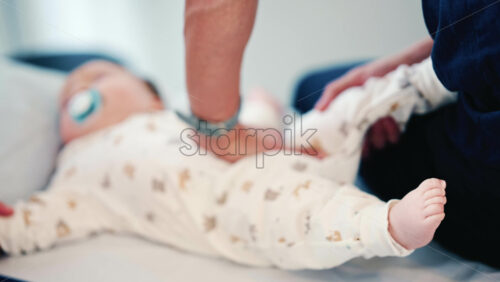 Video - Close up of a caregiver lifting a baby's leg, with focus on the infant's foot and soft background blur