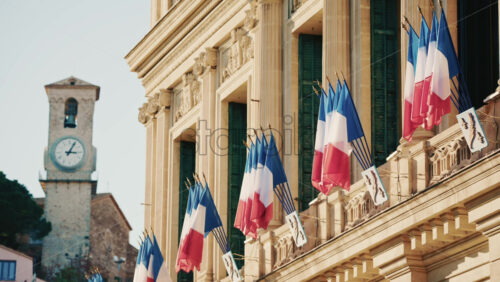 Video - Wide shot of a historic building decorated with French tricolor flags under clear daylight