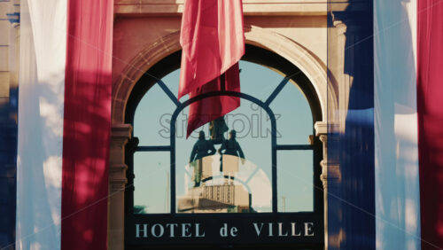 Video - French city hall entrance with tricolor flags and reflection of a monument in the glass