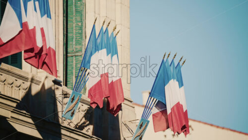 Video - Wide shot of a historic building decorated with French tricolor flags under clear daylight