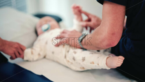 Video - Close up of a caregiver lifting a baby's leg, with focus on the infant's foot and soft background blur