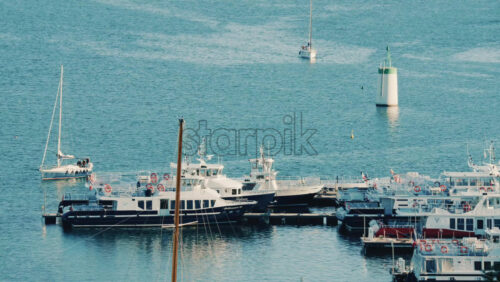 Video - Boats and small vessels docked in a marina with a lighthouse visible in calm blue water