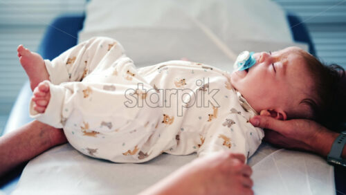 Video - Calm baby wearing a pacifier lying on a medical or therapy table during a pediatric session