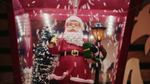 Video - Close up of a Santa Claus figurine inside a decorative snow globe with falling artificial snow