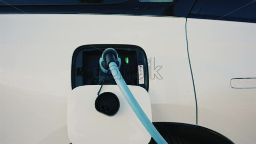 Video - Close up of a white electric car connected to a charging station