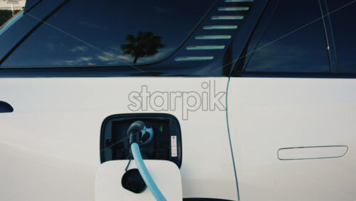 Video - Close up of a white electric car connected to a charging station
