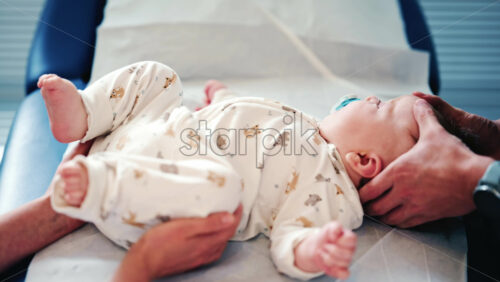 Video - Calm baby wearing a pacifier lying on a medical or therapy table during a pediatric session