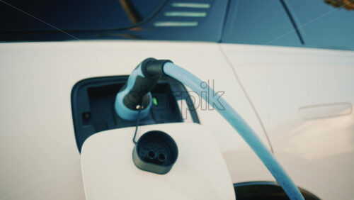 Video - Close up of a white electric car connected to a charging station