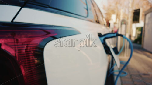Video - Close up of a white electric car connected to a charging station