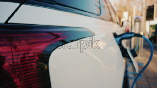 Video - Close up of a white electric car connected to a charging station