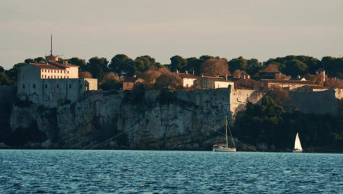 Video - Sailboat floating on calm Mediterranean water in front of the historic Fort Carre in Antibes