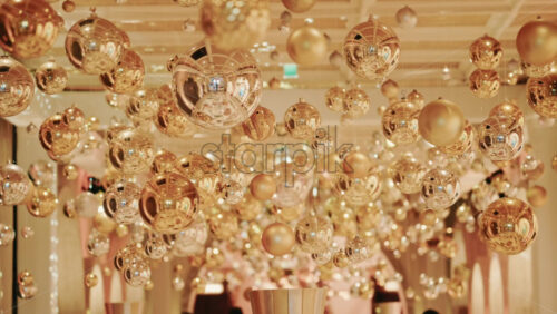 Video - Decorative golden Christmas ornaments suspended in an elegant indoor display