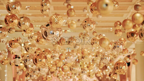 Video - Decorative golden Christmas ornaments suspended in an elegant indoor display