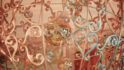 Video - Close up of decorative Christmas ornaments hanging from an ornate metal structure