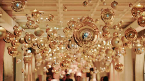 Video - Decorative golden Christmas ornaments suspended in an elegant indoor display