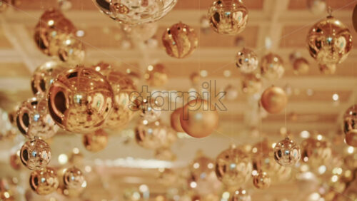 Video - Decorative golden Christmas ornaments suspended in an elegant indoor display