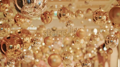 Video - Decorative golden Christmas ornaments suspended in an elegant indoor display