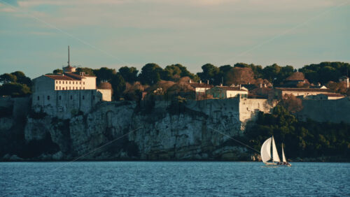 Video - Sailboat floating on calm Mediterranean water in front of the historic Fort Carre in Antibes