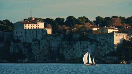 Video - Sailboat floating on calm Mediterranean water in front of the historic Fort Carre in Antibes