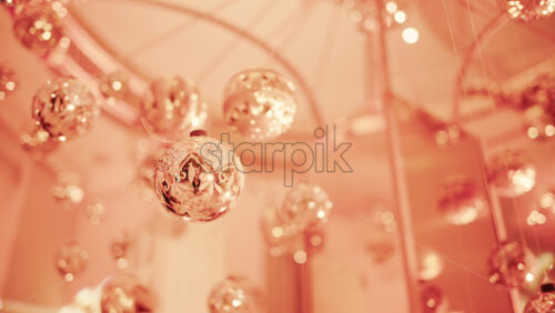 Video - Close up view of elegant golden Christmas ornaments suspended indoors with warm festive lighting