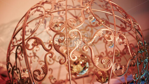 Video - Close up of decorative Christmas ornaments hanging from an ornate metal structure