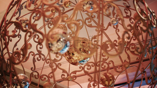 Video - Close up of decorative Christmas ornaments hanging from an ornate metal structure