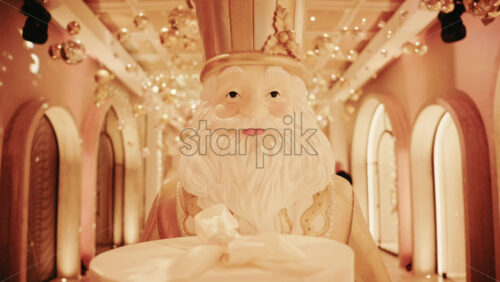 Video - Close up of a Santa Claus figure inside a festive Christmas installation with warm lights and ornaments