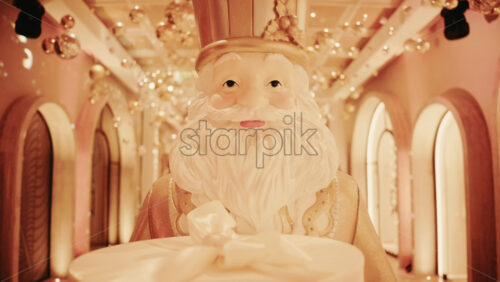 Video - Close up of a Santa Claus figure inside a festive Christmas installation with warm lights and ornaments