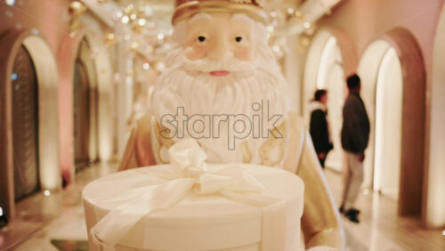 Video - Close up of a Santa Claus figure inside a festive Christmas installation with warm lights and ornaments