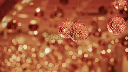 Video - Hanging Christmas ornaments glowing against a soft background of golden bokeh lights