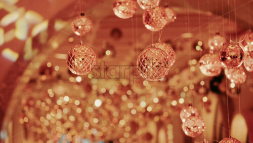 Video - Hanging Christmas ornaments glowing against a soft background of golden bokeh lights