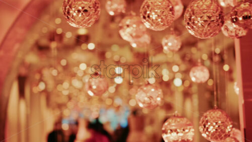 Video - Hanging Christmas ornaments glowing against a soft background of golden bokeh lights