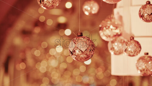 Video - Hanging Christmas ornaments glowing against a soft background of golden bokeh lights