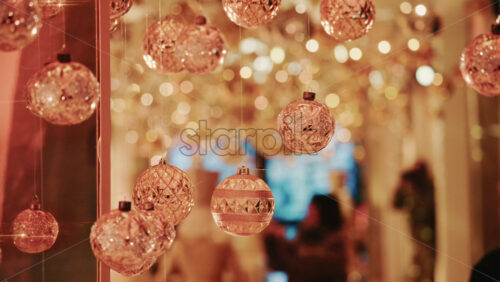 Video - Hanging Christmas ornaments glowing against a soft background of golden bokeh lights