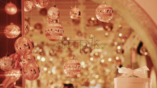 Video - Golden Christmas ornaments suspended above a decorative gift box in a festive indoor setting