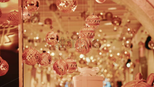 Video - Golden Christmas ornaments suspended above a decorative gift box in a festive indoor setting