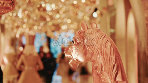 Video - Elegant close-up of a decorative horse statue displayed inside a warmly lit hallway filled with golden holiday lights and ornaments