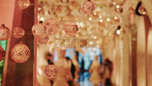 Video - Golden Christmas ornaments suspended above a decorative gift box in a festive indoor setting