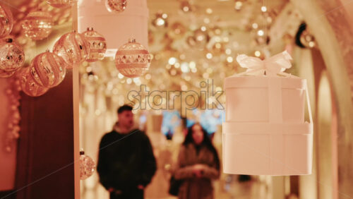 Video - Golden Christmas baubles hanging in a softly illuminated indoor corridor, creating a warm and magical holiday ambiance